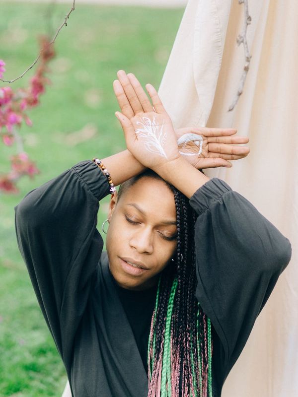 Silhouette of a woman in a calm, balanced pose against a soft pink background.