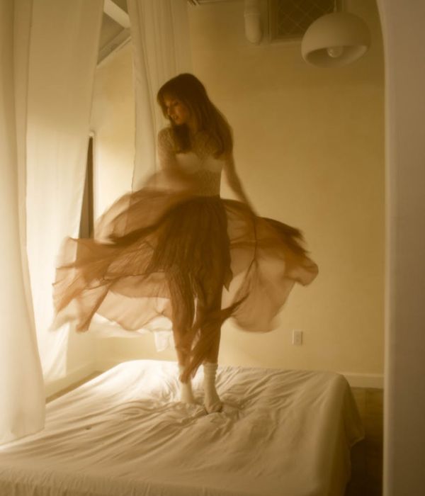 Woman performing a gentle, flowing movement in a bright, airy room.